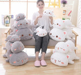Woman sitting on a chair surrounded by various plush toys in a bright room.