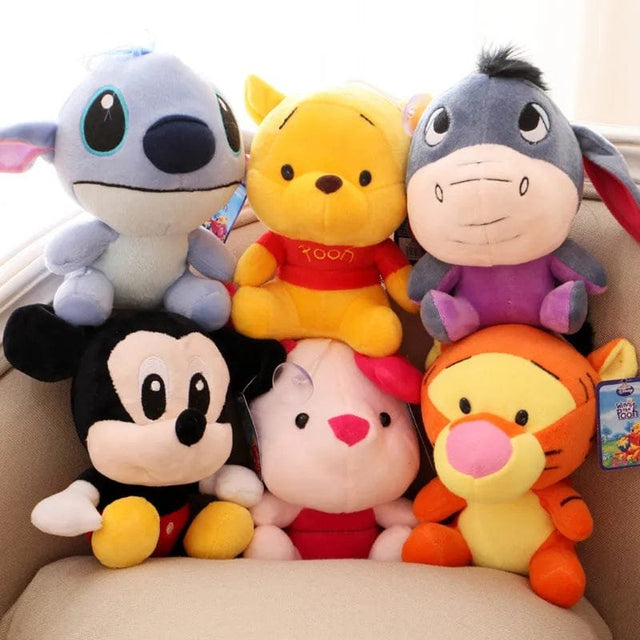 Stack of colorful plush toys including Mickey Mouse, Winnie the Pooh, and friends on a beige surface.