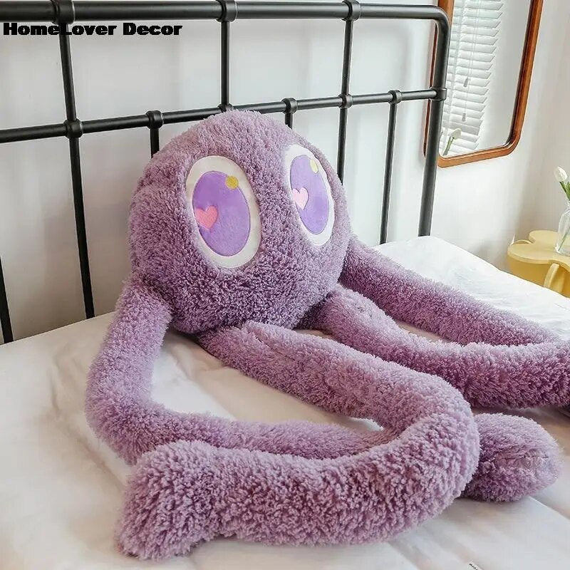 Purple plush toy with heart eyes on a bed