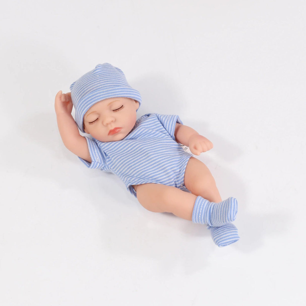 Newborn baby doll in blue striped outfit and hat on a white background