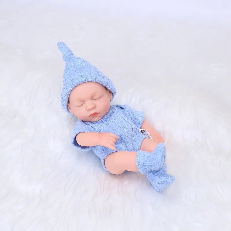 Newborn baby in a blue outfit and hat lying on a white surface