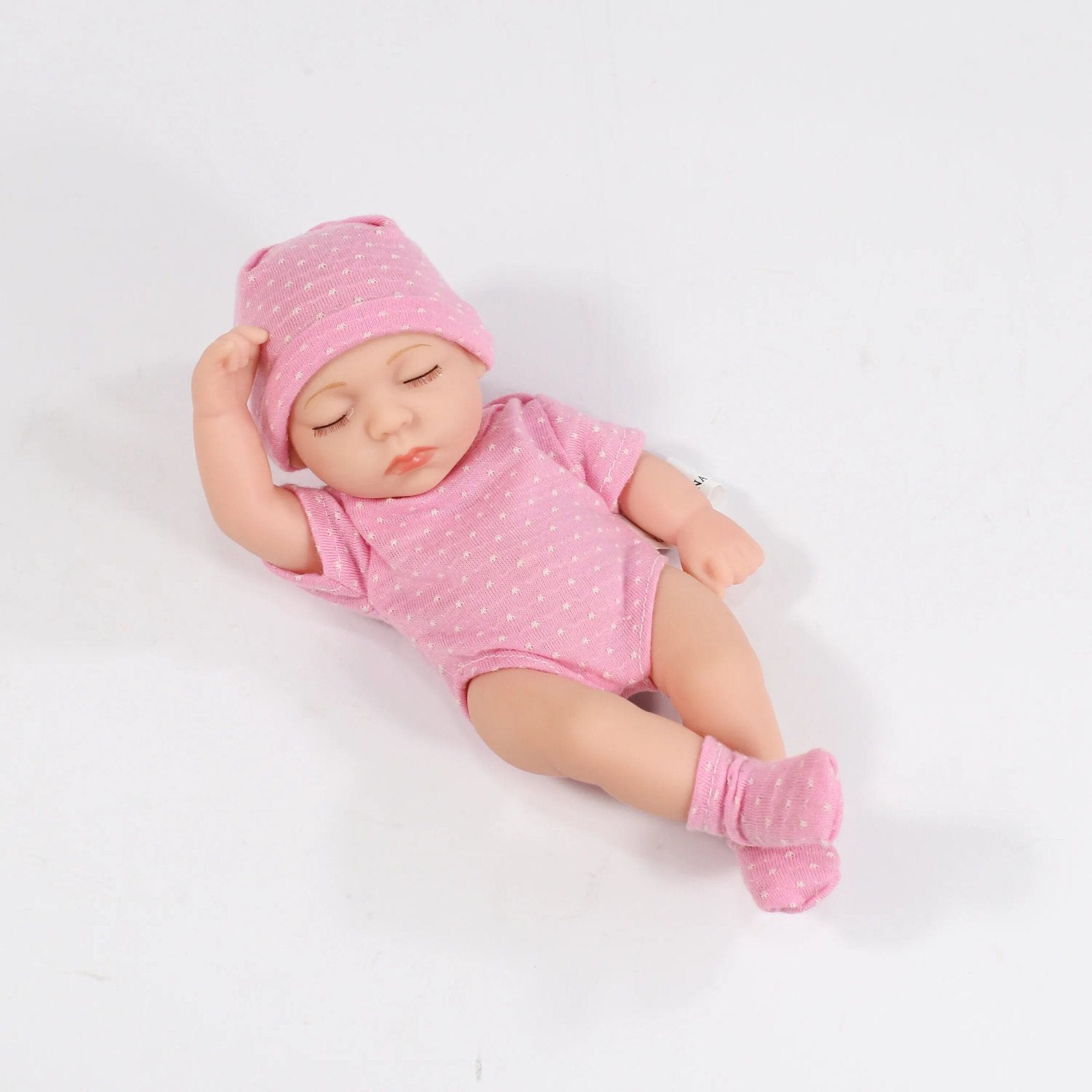 Sleeping baby doll in pink outfit and hat on a white background