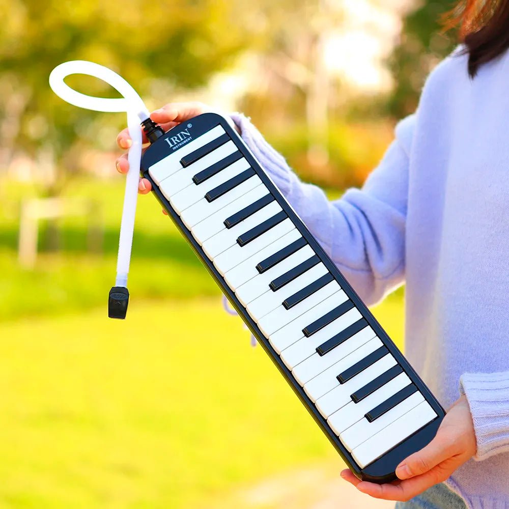Person holding a black and white keyboard-style instrument outdoors