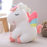 Plush unicorn toy with a rainbow-colored horn and pink mane on a light surface.