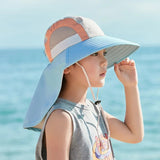 Child wearing a colorful sun hat with a beach background