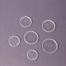 Six transparent drawing gears from the colourful Spirograph set for making layered patterns with pens.