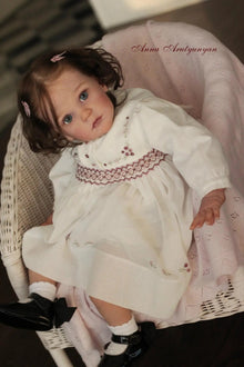 23-inch Mattia reborn doll in a white lace dress with rooted hair for realistic nurturing play and collecting.