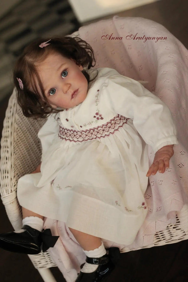 23-inch Mattia reborn doll in a white lace dress with rooted hair for realistic nurturing play and collecting.