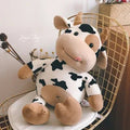 Cute cow plushie milk cattle stuffed toy styled on a chair as soft bedroom decor and a kids cuddle toy.