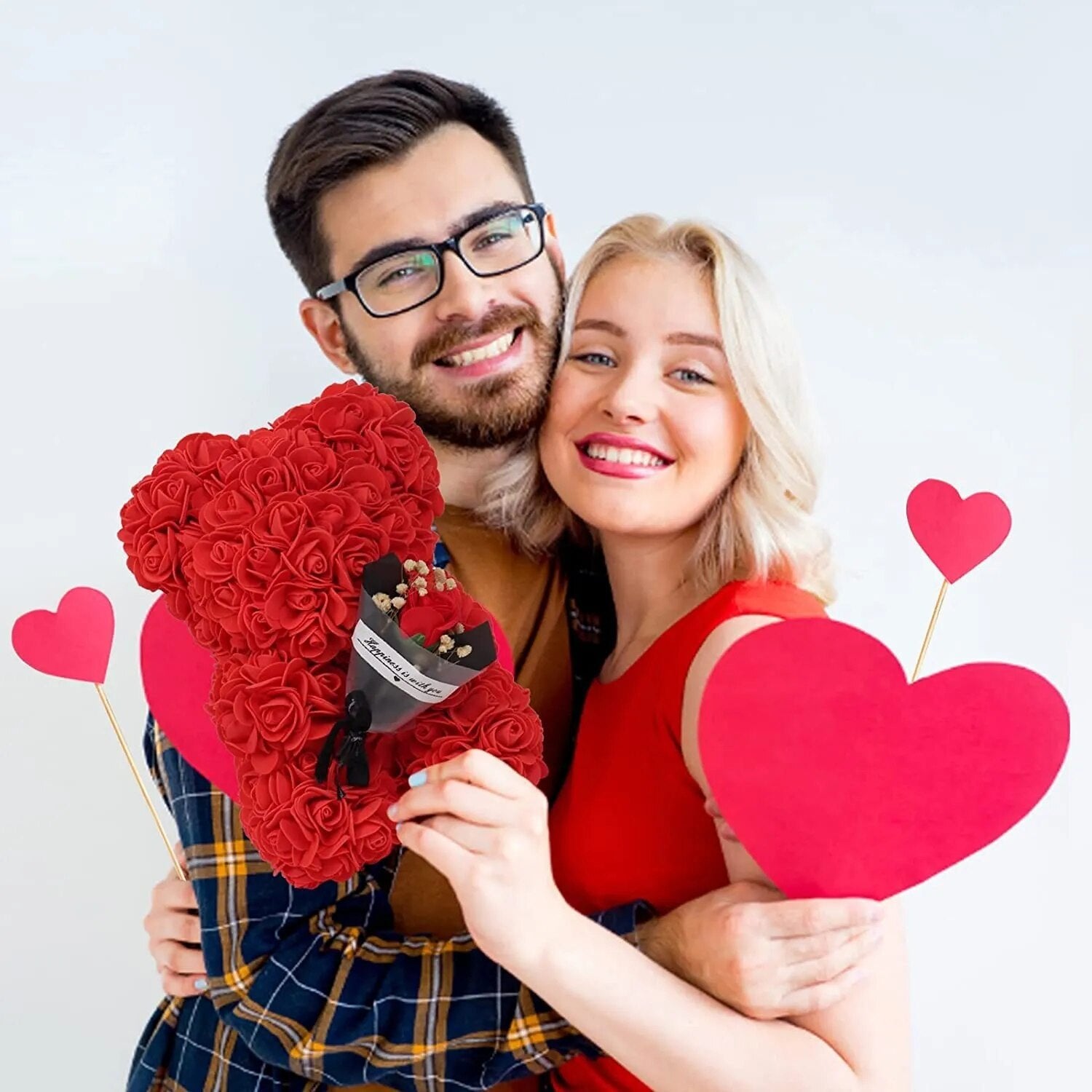 Couple holding heart props alongside the Rose Bear gift box, a romantic present idea for engagements and anniversaries.