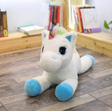 Plush unicorn toy on a wooden floor with books in the background