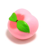 Pink peach-shaped object with a green leaf on a white background