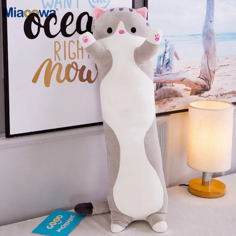 Cat-shaped plush toy on a bed with a lamp and decor in the background