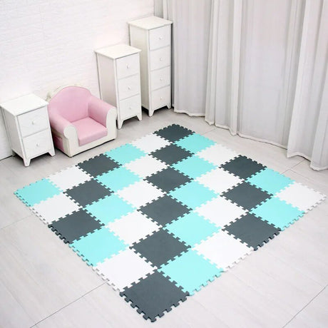 Checkered foam puzzle mat on a floor with white furniture and pink chair in the background