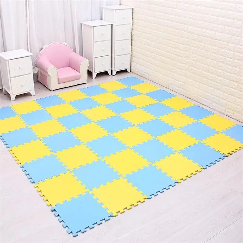 Checkered blue and yellow foam mat on a floor with white furniture and pink chair in the background.