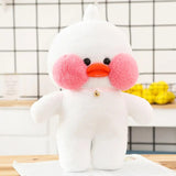 White plush toy with pink cheeks and orange beak on a wooden surface with a grid-patterned wall in the background.