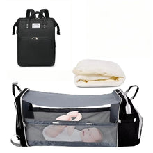 Black 3-in-1 backpack with white mattress and gray foldable baby crib for portable naps while traveling.