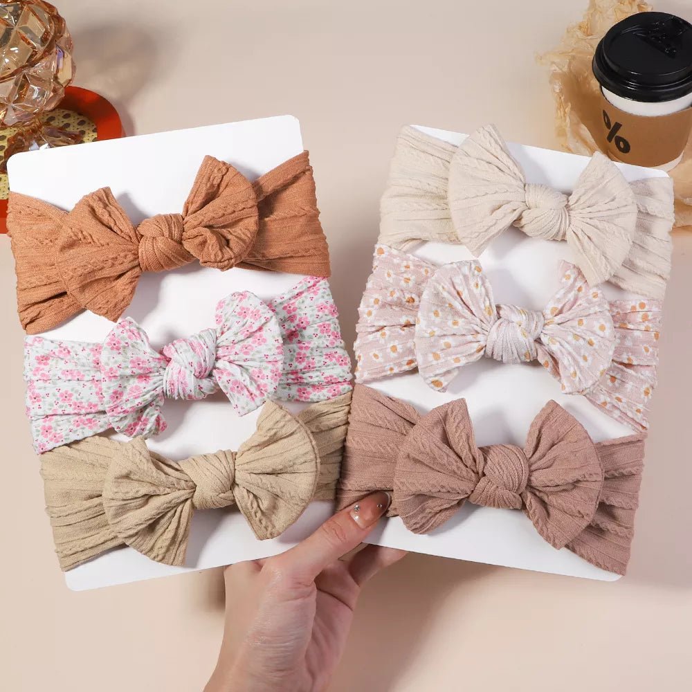 Set of decorative bows on a white surface with a hand holding one of them.