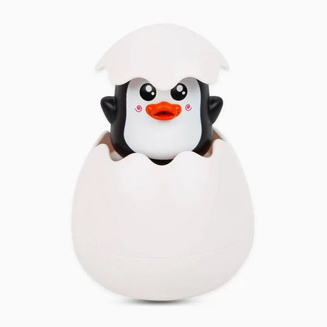 Penguin toy emerging from a white egg on a white background