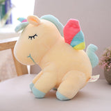 Plush unicorn toy with rainbow-colored wings on a light surface.