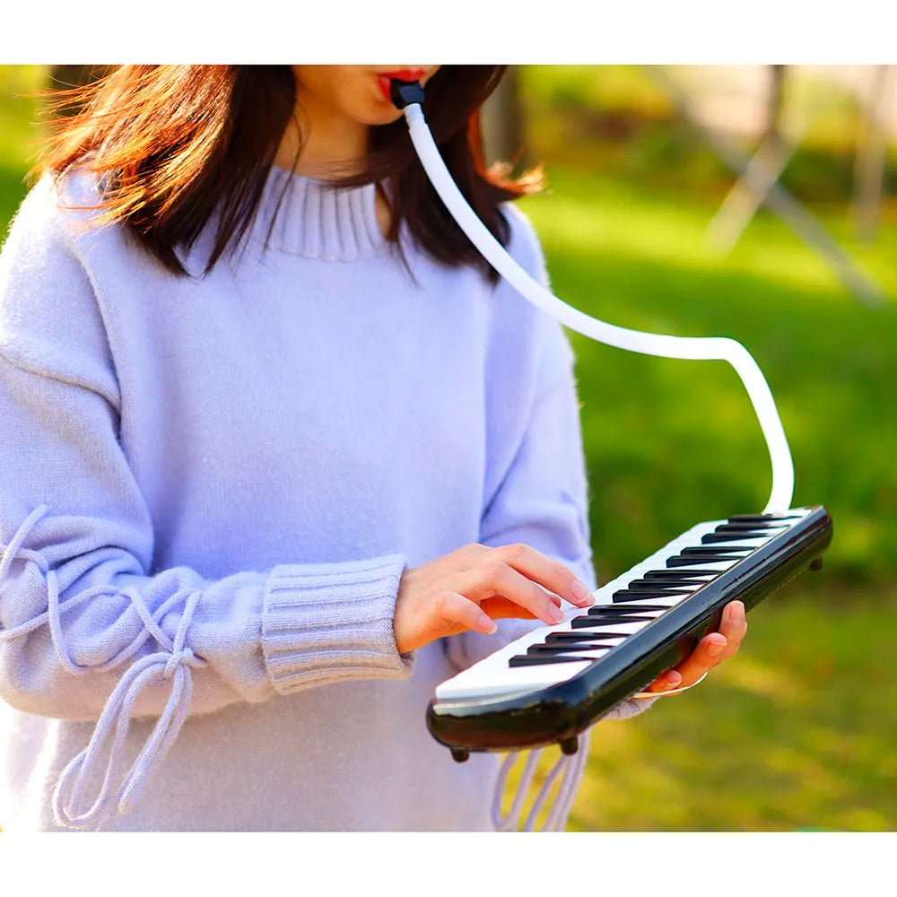 Person playing a small keyboard outdoors with a blurred green background
