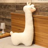 Plush llama toy against a wooden wall with a lamp on a shelf.