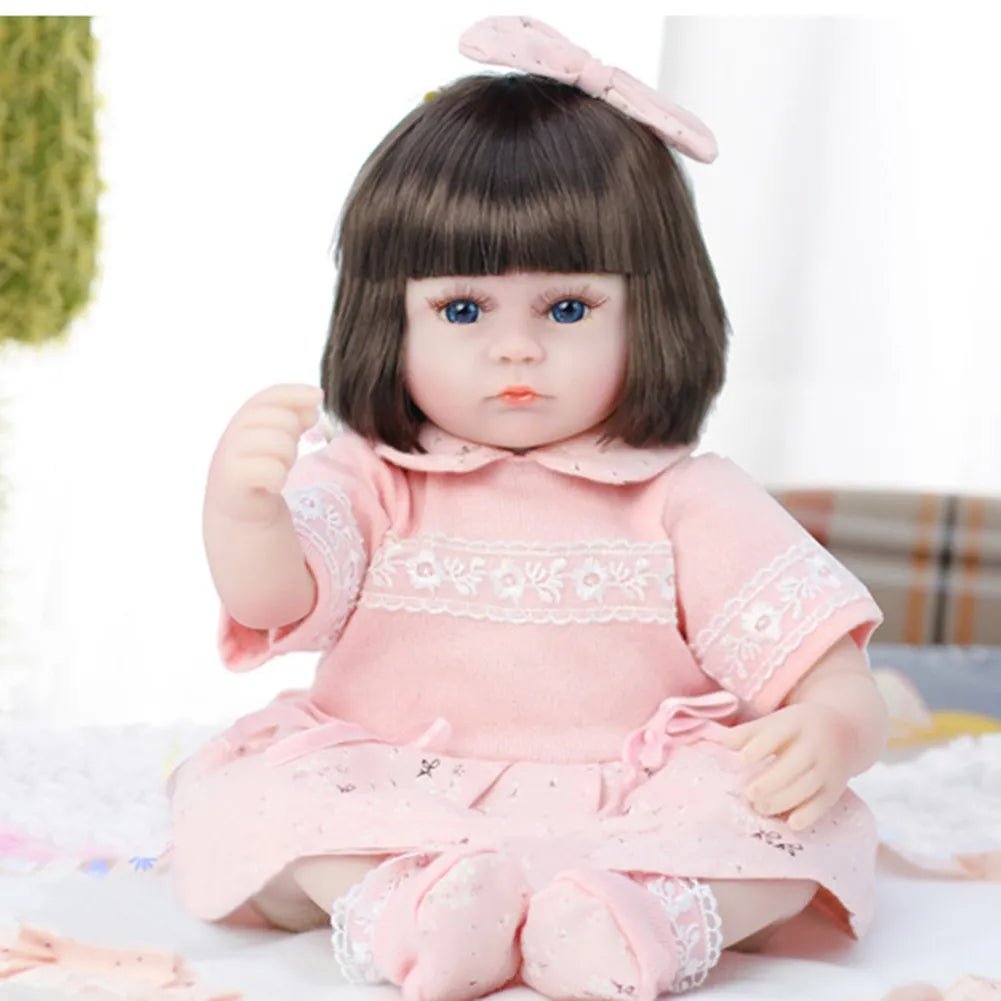 Realistic baby doll in a pink outfit with a bow.