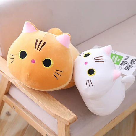Two cat-shaped plush toys, one orange and one white, sitting on a wooden surface.