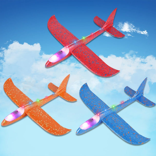 Three colorful toy airplanes flying against a blue sky with clouds.
