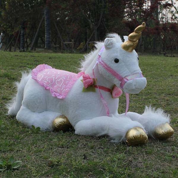 Plush unicorn toy with pink saddle blanket and gold hooves on grass