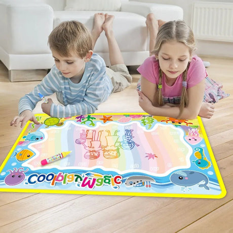 Two children playing with a colorful drawing mat on a wooden floor.
