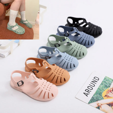 Colorful children's sandals displayed on a white surface with a magazine corner.