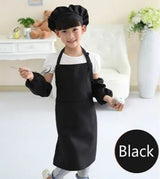Child wearing a black apron and chef hat in a kitchen setting