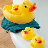 Three yellow rubber ducks on a white surface with a blue towel underneath.