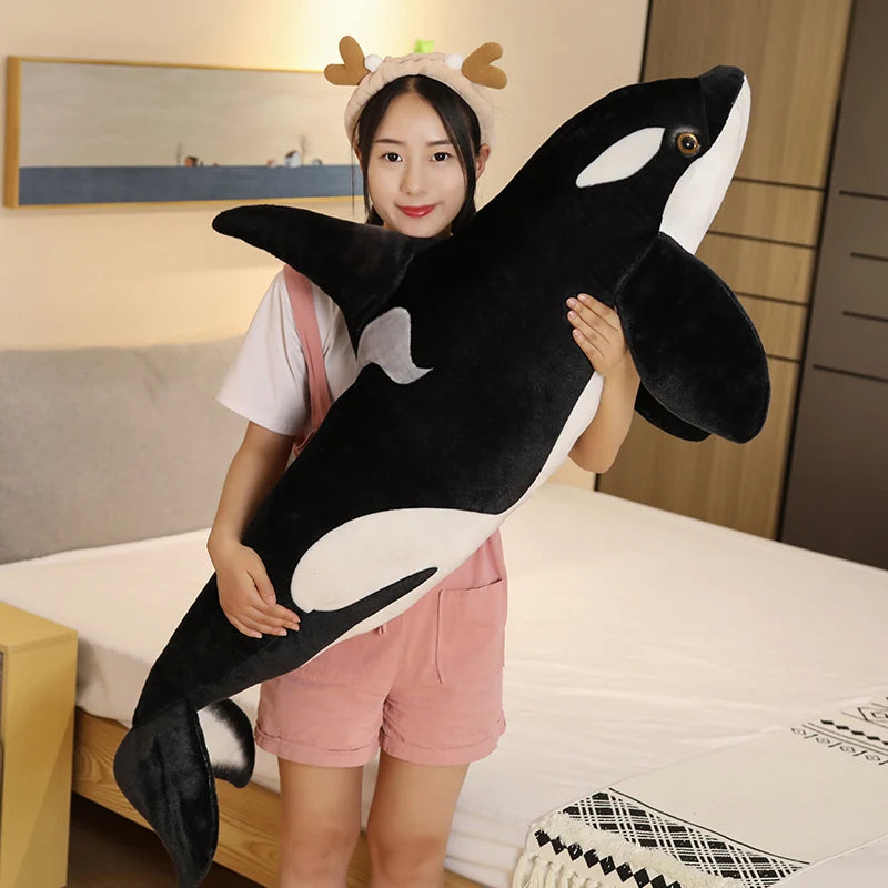Person holding a large plush orca whale.