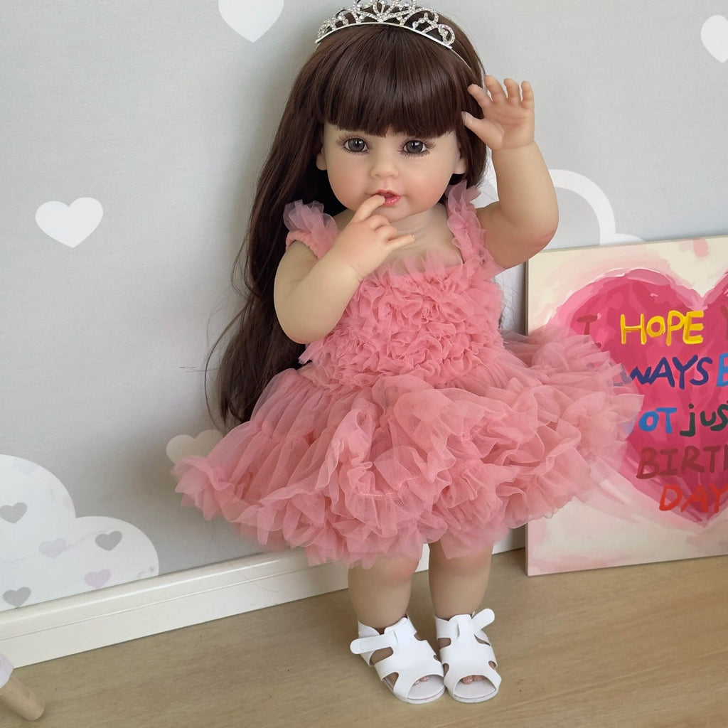 Soft silicone Reborn Toddler Doll in a pink princess outfit with tiara styled against a party backdrop for birthday gifting and photo play.