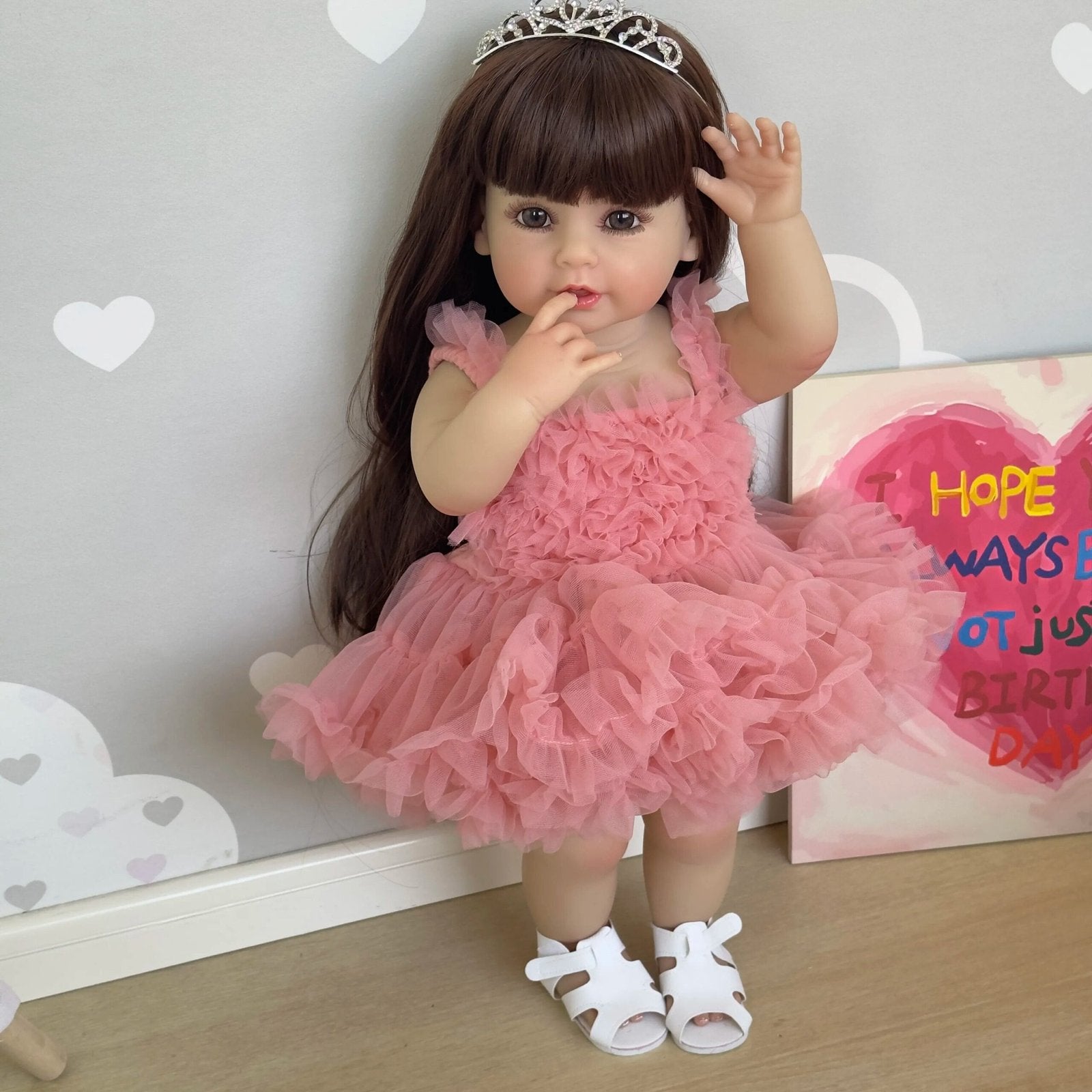Soft silicone Reborn Toddler Doll in a pink princess outfit with tiara styled against a party backdrop for birthday gifting and photo play.