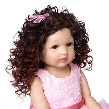 Silicone Reborn Toddler Doll with curly brown hair and pink outfit, a soft touch fashion doll for cuddling and keepsake collecting.