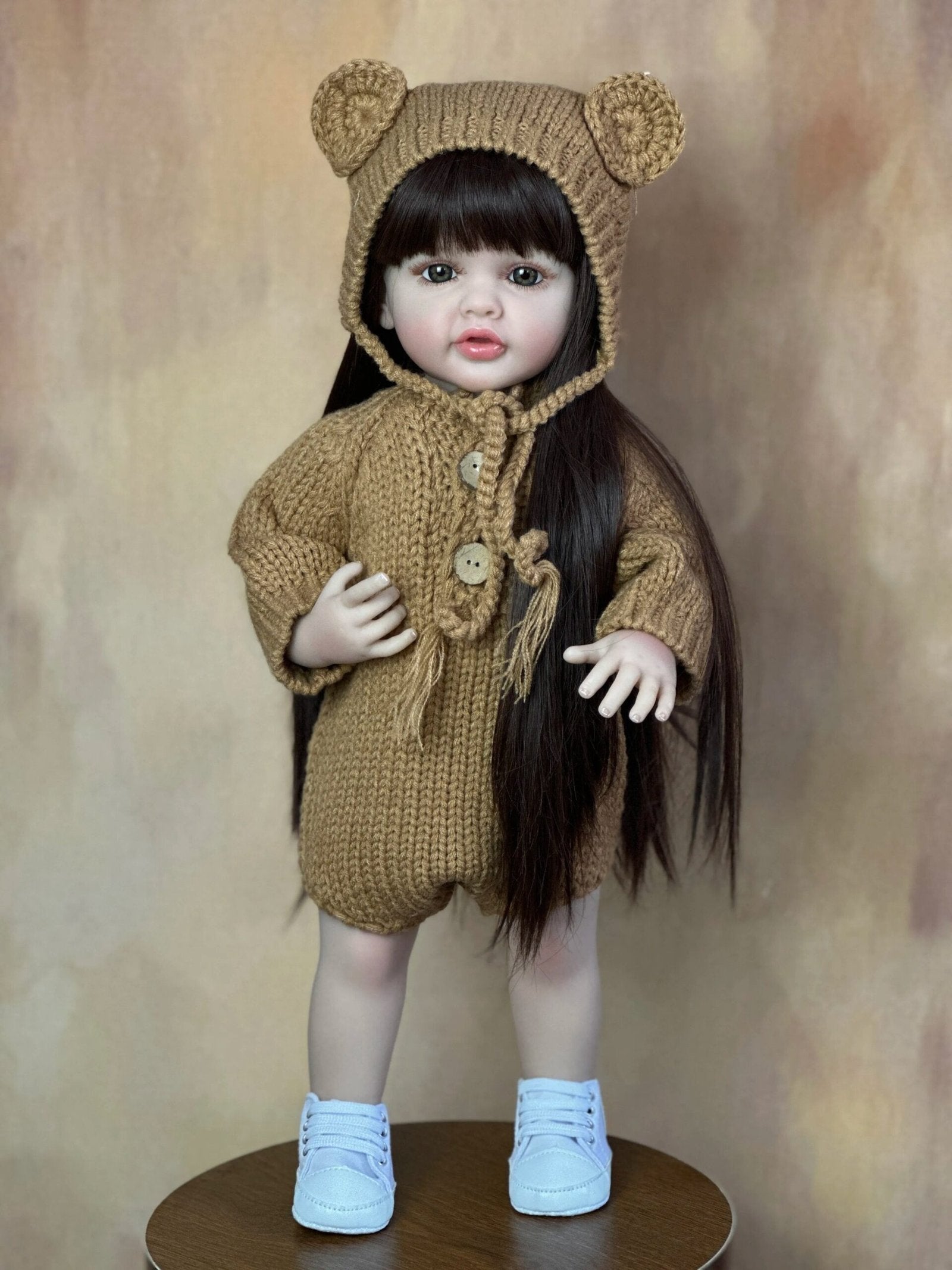 Standing Reborn Doll in a brown bear knit outfit presented as a sweet present, a soft silicone doll for cuddles and display.