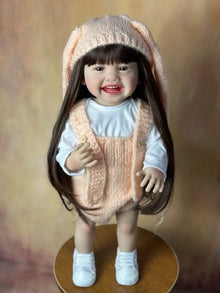 Side angle of the Standing Reborn Doll in a bunny-ear knit outfit, a soft silicone baby doll for cuddling and cosy play.