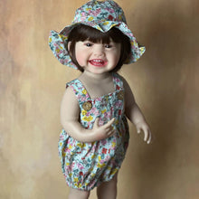 Standing Reborn Doll in a floral hat and romper, a silicone baby doll for summer dress-up play and collector gifting.