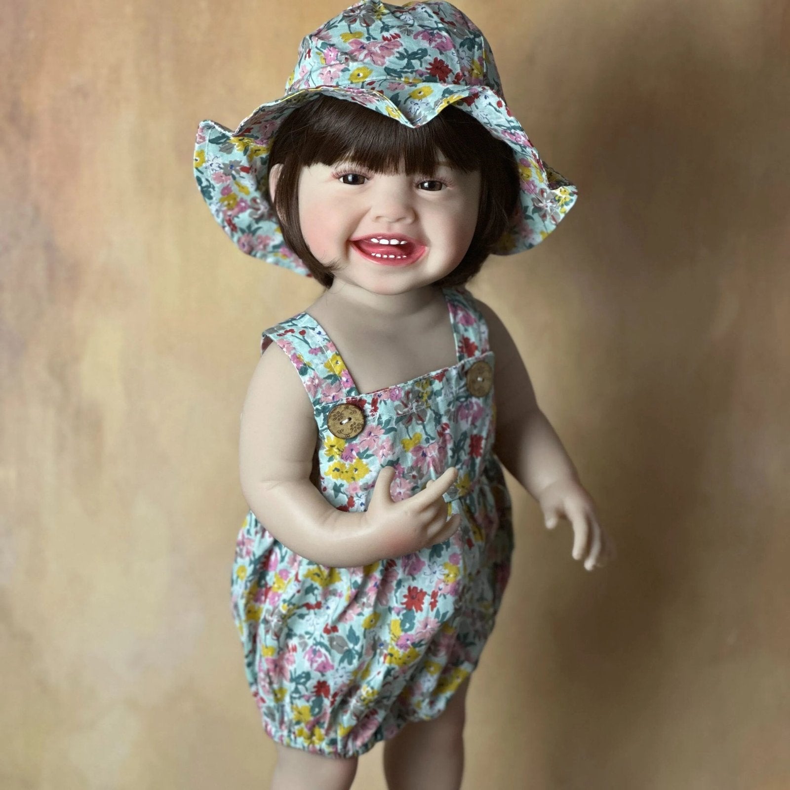 Standing Reborn Doll in a floral hat and romper, a silicone baby doll for summer dress-up play and collector gifting.