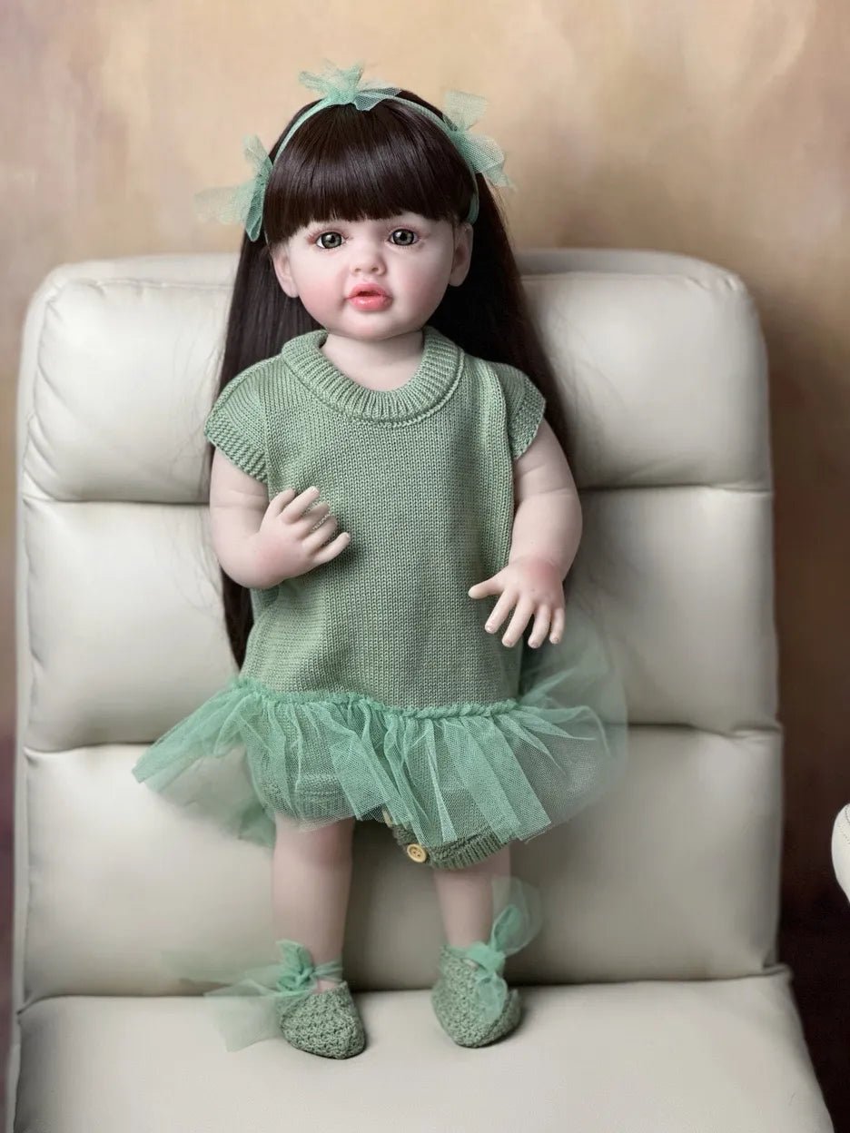 Close-up of the Standing Reborn Doll in a green dress on a chair, a classic silicone baby doll for gifting and quiet play.