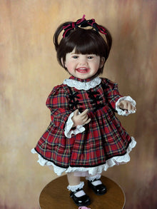Close-up of the Standing Reborn Doll in a red plaid dress with lace trim, a delightful silicone doll for festive gifting.