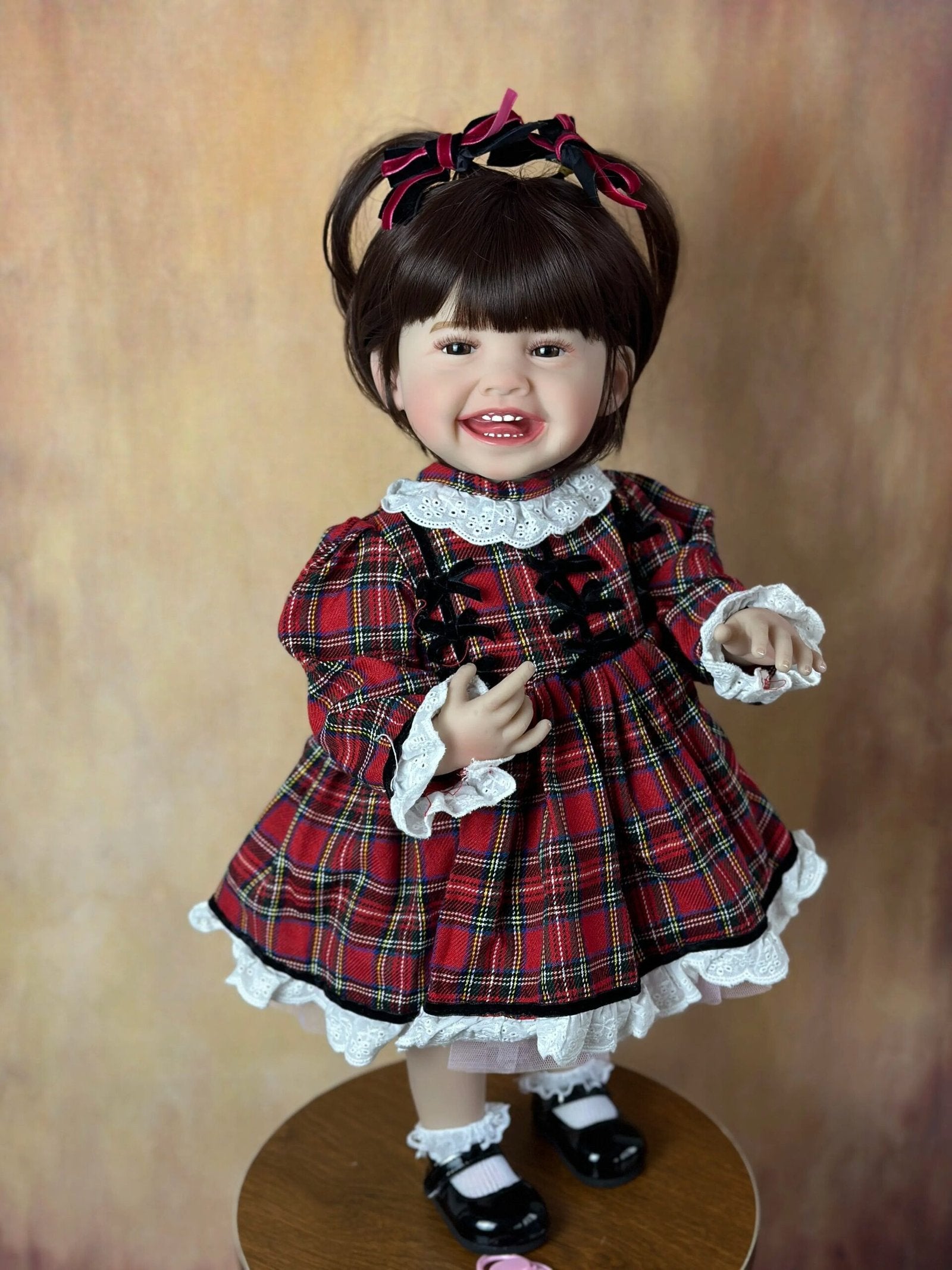 Close-up of the Standing Reborn Doll in a red plaid dress with lace trim, a delightful silicone doll for festive gifting.