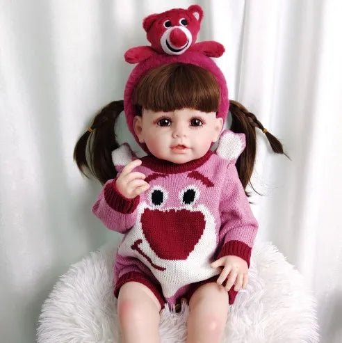 Waterproof Reborn Doll wearing a pink heart outfit with matching hat, a curly hair silicone doll for everyday cuddles and dress-up play.