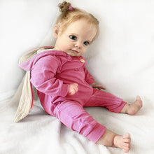 58cm Reborn Maggi Baby Doll in soft touch silicone with rooted hair lying down for nap-time pretend play and cuddles.