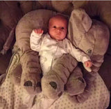 Baby lying on a large plush elephant toy on a couch