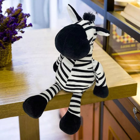Plush zebra toy sitting on a wooden surface with a blurred background