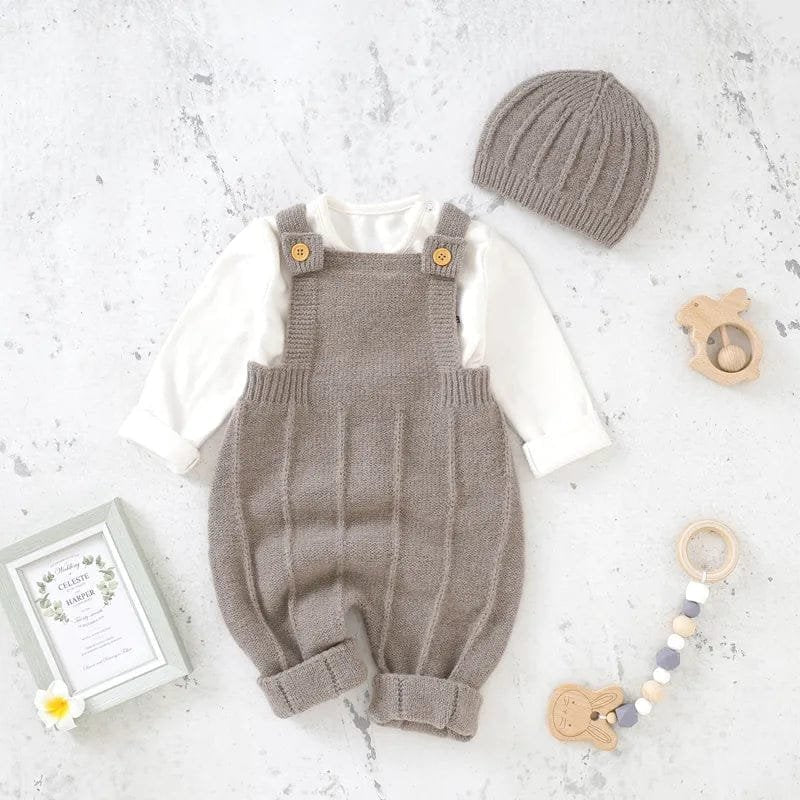 Knitted baby romper with overalls, hat, and toys on a light background
